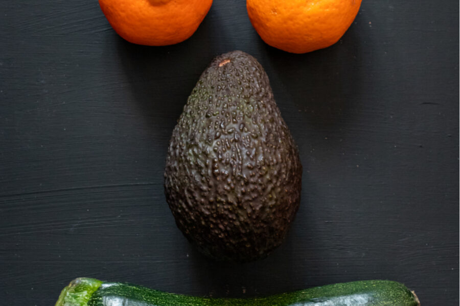 A funny face made up of 2 oranges, an avocado and a courgette as a metaphor for healthy eating