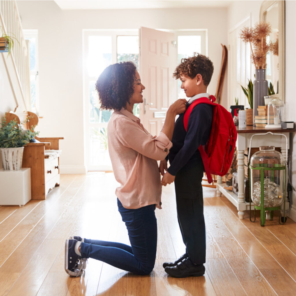 A mother kneeling in front of her son who's going back to school